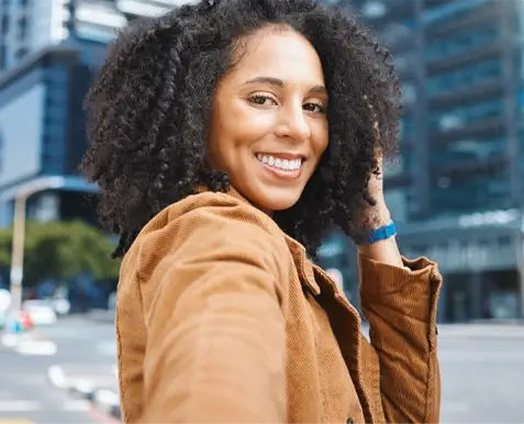 photo of woman holding hair and looking at camera smiling